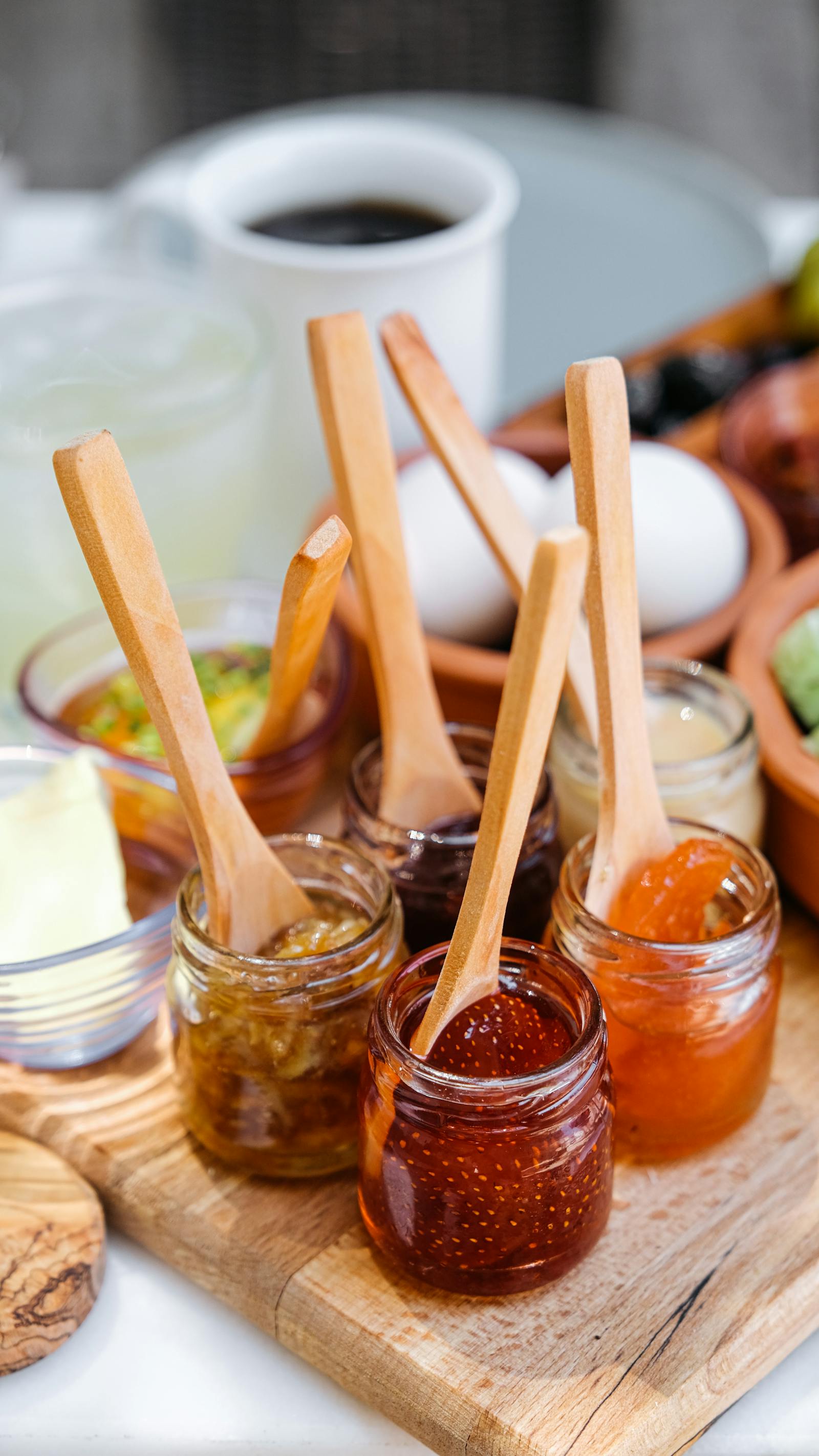 Open jars of preserves with tasting spoons on a breakfast table