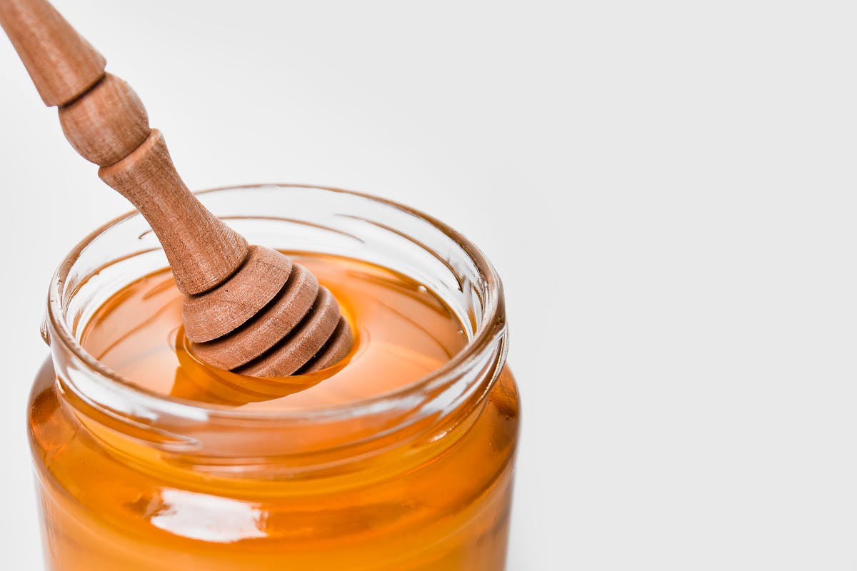 A jar of wild blueberry honey with a wooden dipper